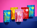 Five MshrooM FX Extra Strength Bulk Mushroom Gummies 50 count bags in all four flavors Blue Razzberry Mango Pink Lemonade and Strawberry displayed in staggered arrangement on navy blue surface against pink background showing full product lineup with 21 plus age badge and 7.1 oz net weight